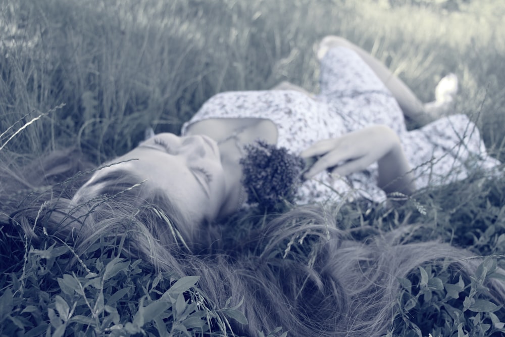 woman in pink dress laying on grass during daytime