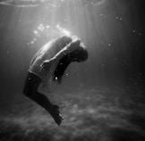 grayscale photo of woman drowning in water