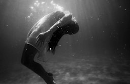 grayscale photo of woman drowning in water