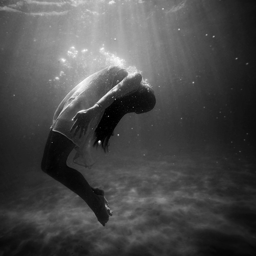 grayscale photo of woman drowning in water