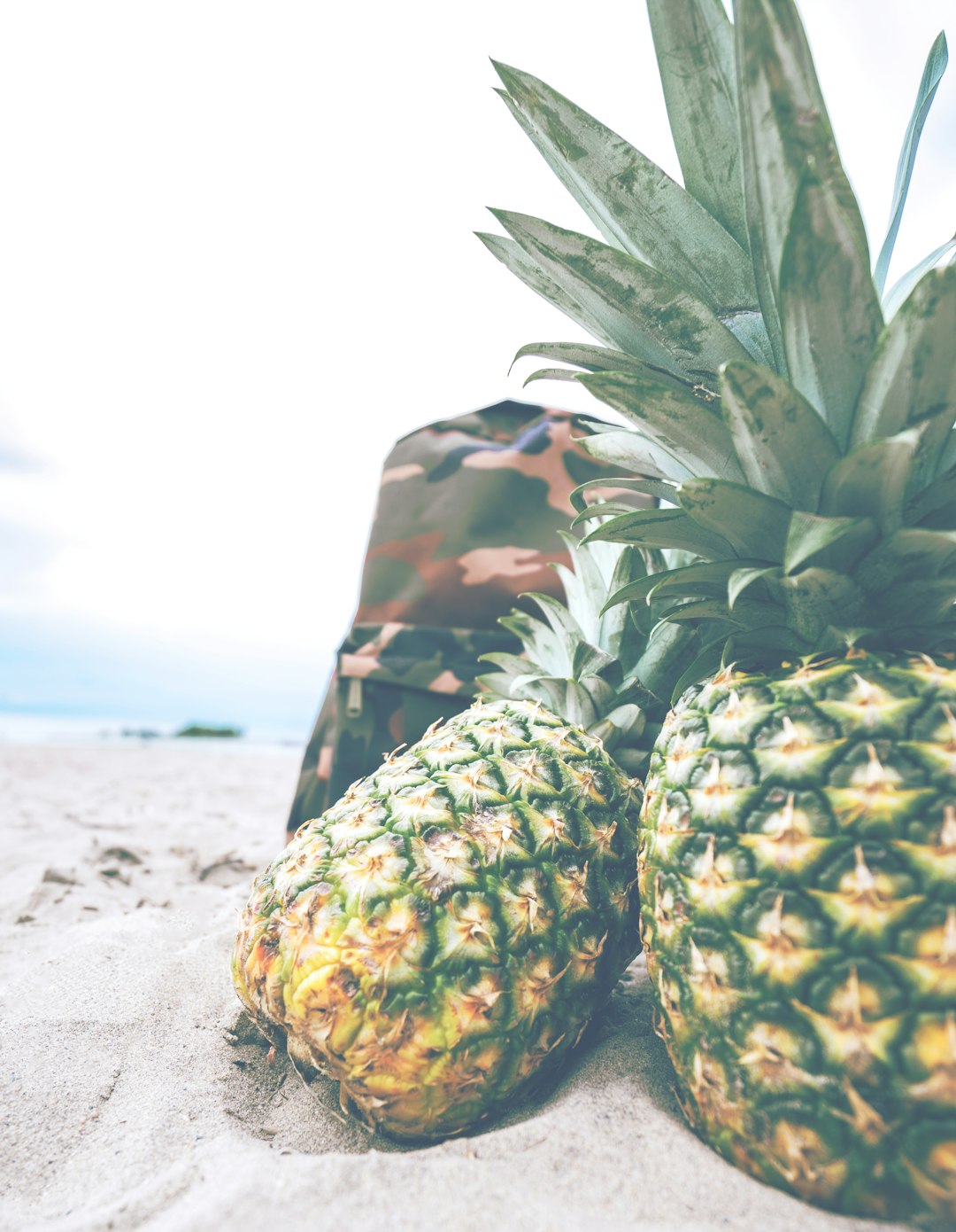 two pineapples on gray sand