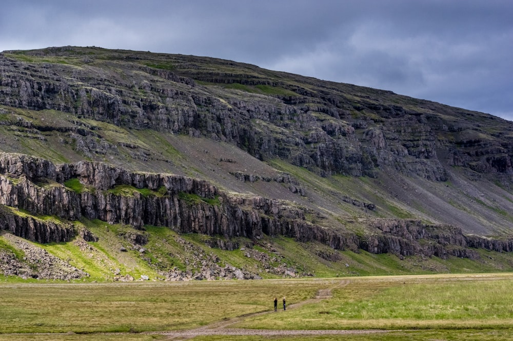 two people standing on field near cliff