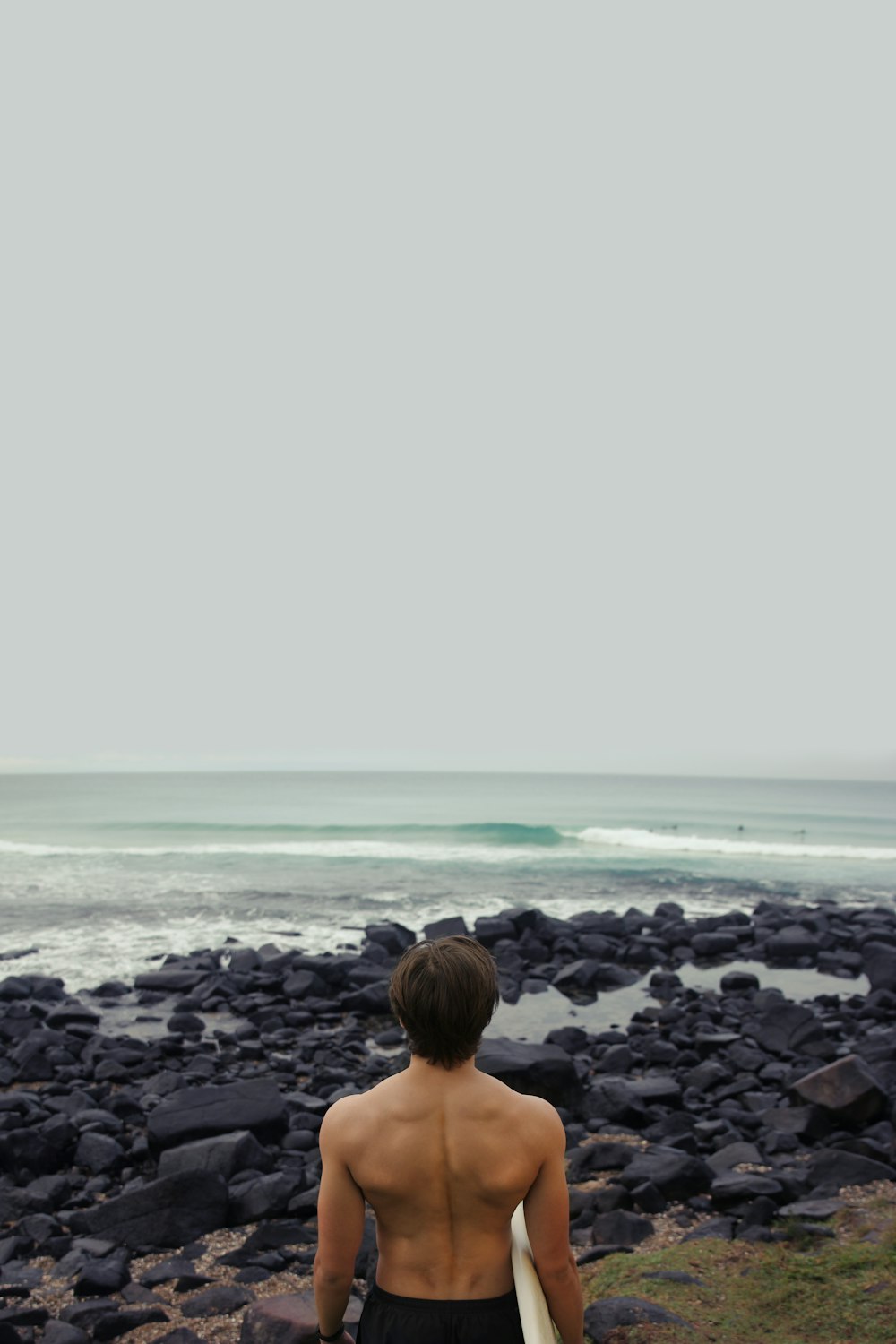 바다 근처에서 서핑 보드를 들고 있는 남자