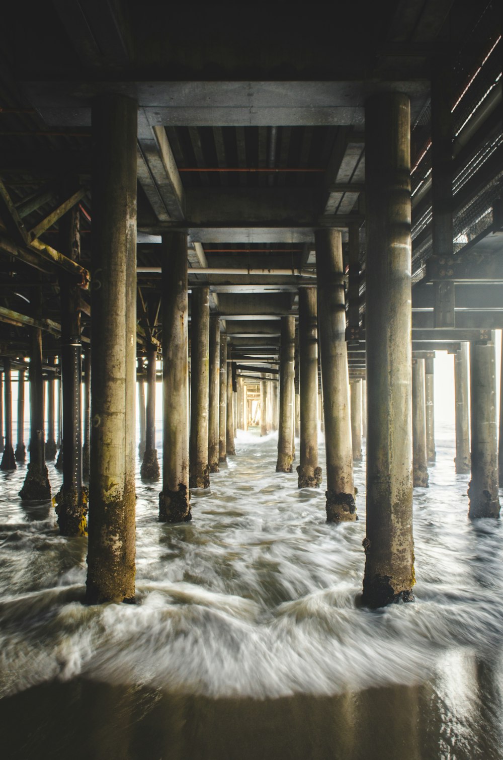 Pontile di legno marrone e nero sotto l'acqua dell'oceano