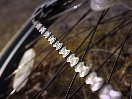 Close-up of bicycle chain being cleaned with a cloth on a sunny day.