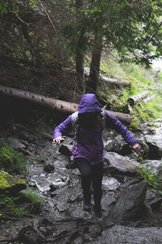 A person wearing an Aquashield jacket hiking through a misty forest trail.