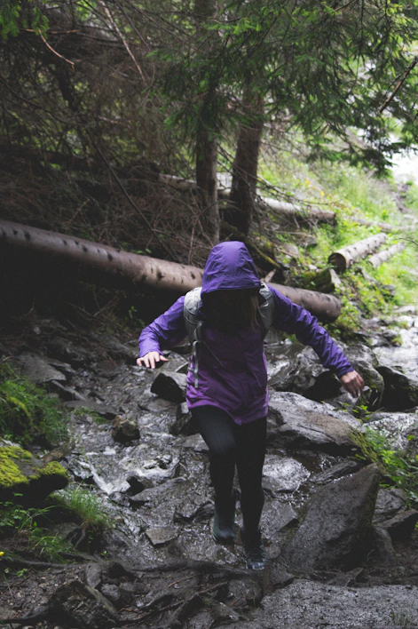 Close-up of rugged waterproof pants navigating a rocky mountain trail under rain.