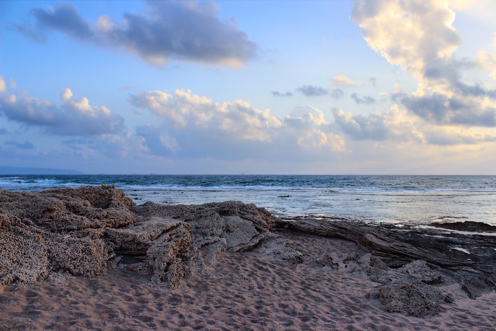 photo of sands and rocks near body of water