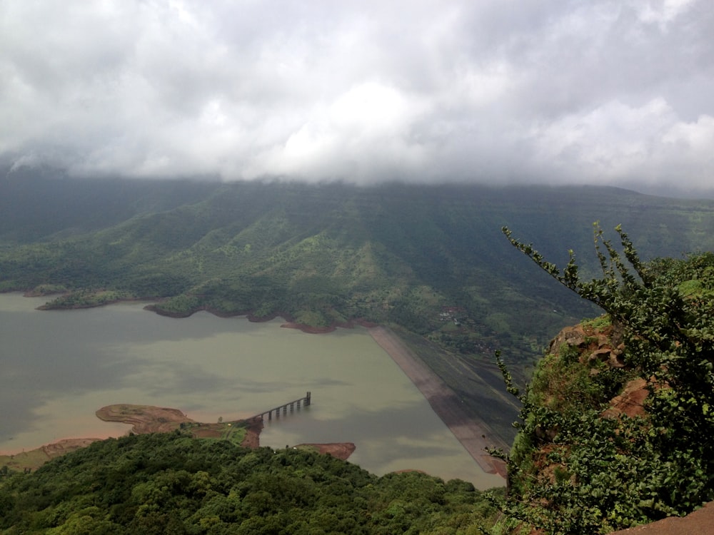 body of water surrounded by trees under cloudy skies