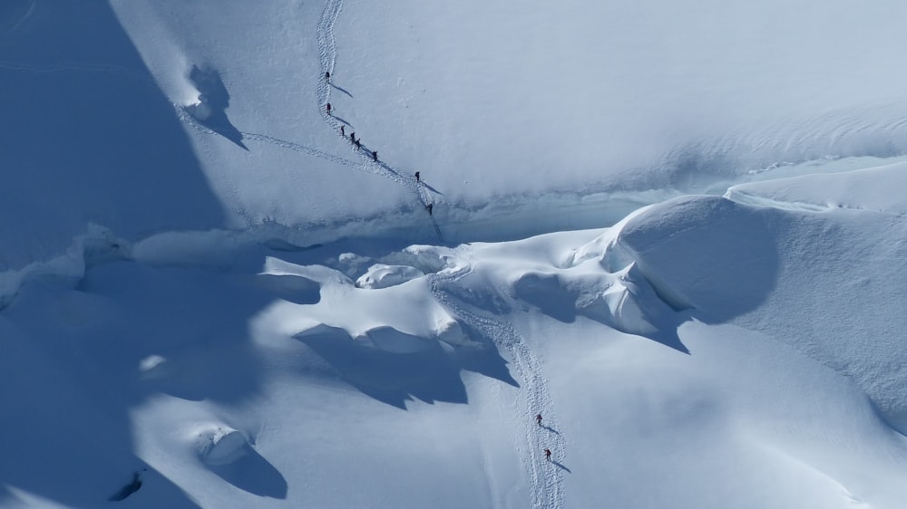 Fotografía aérea de un grupo de personas caminando sobre la nieve