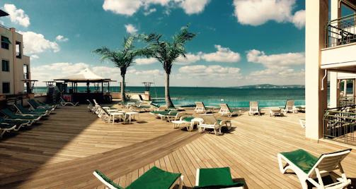 Private wooden deck with sun loungers and umbrellas overlooking crystal-clear Mediterranean waters.