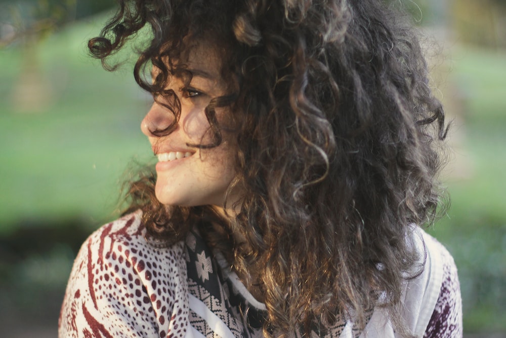 A smiling young woman with dark curly hair