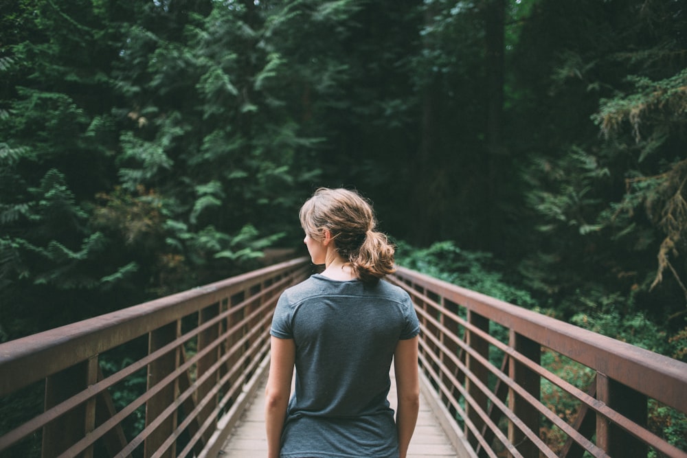 selective focus photography of woman in black t-shirt standing on bridge