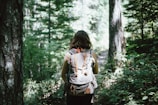 woman in sleeveless top and backpack surrounded by trees during daytime