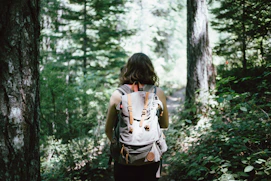 woman in sleeveless top and backpack surrounded by trees during daytime