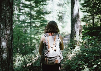 woman in sleeveless top and backpack surrounded by trees during daytime