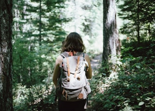 woman in sleeveless top and backpack surrounded by trees during daytime