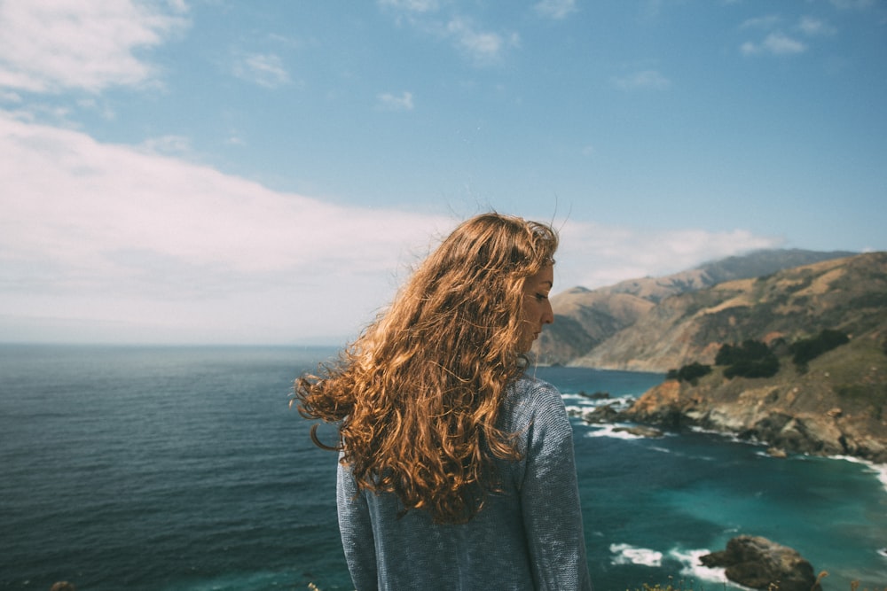 donna in piedi di fronte all'oceano durante il giorno