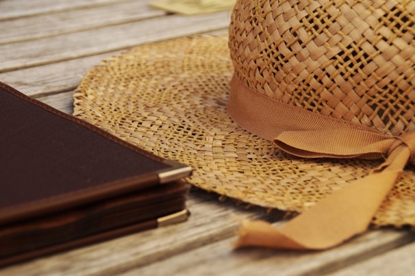 A stylish hat with a unique graphic print displayed on a rustic wooden table alongside sketchbooks.