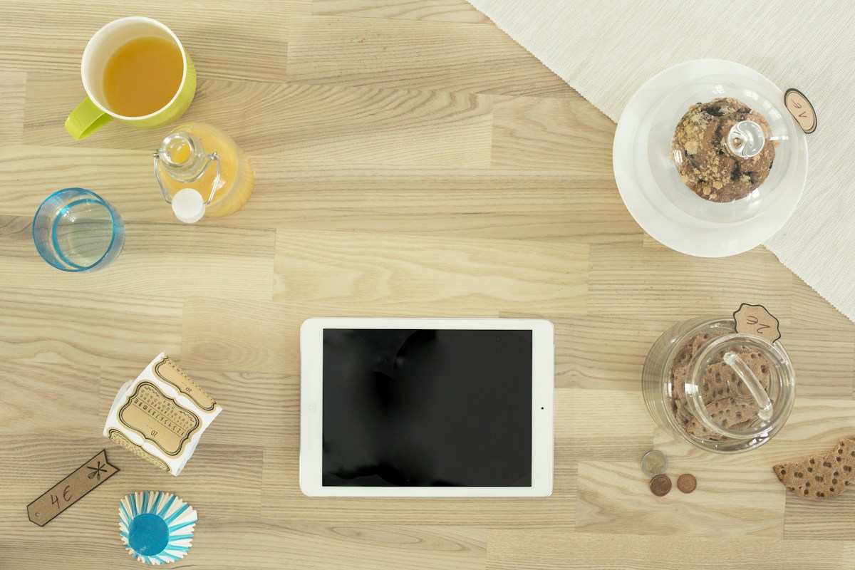 White iPad displaying a list of healthy college snacks on a wooden table, ideal for dorm room snack ideas.