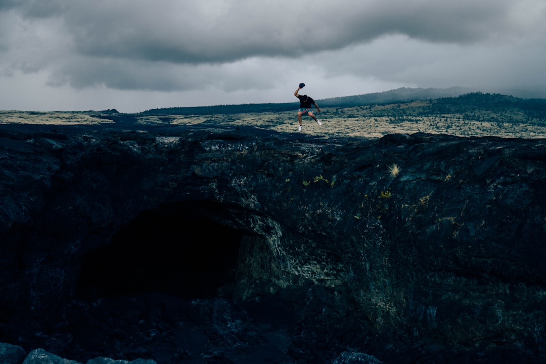 man standing on rock formation during daytime