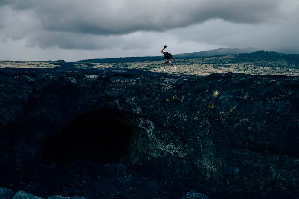 man standing on rock formation during daytime