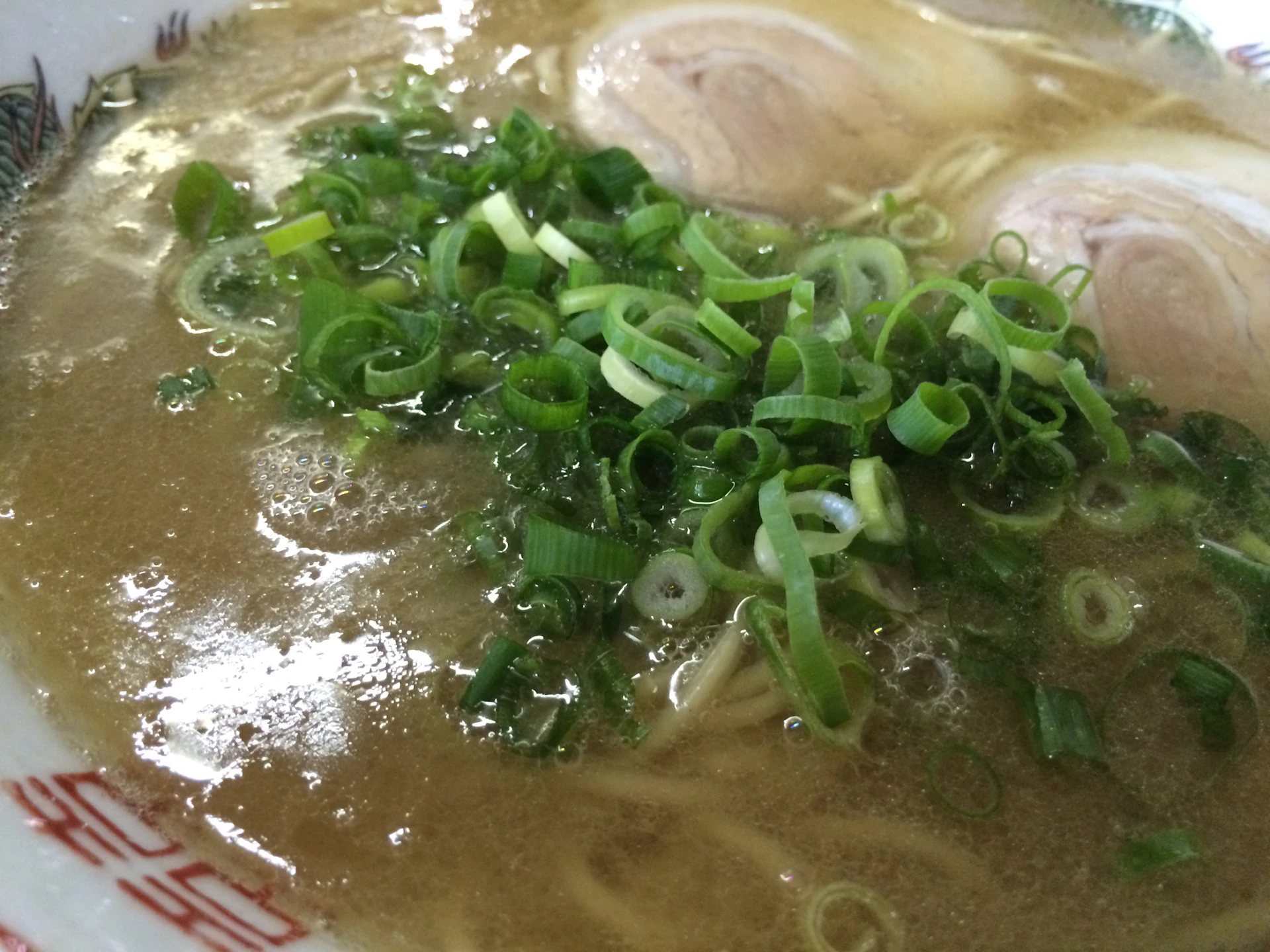 A warm bowl of steaming ramen with tender slices of pork, a perfectly boiled egg, and fresh herbs floating atop the savory broth.