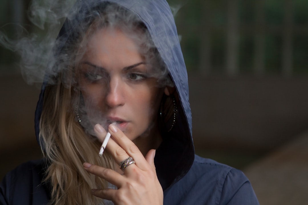 woman wearing hoodie while holding cigarette