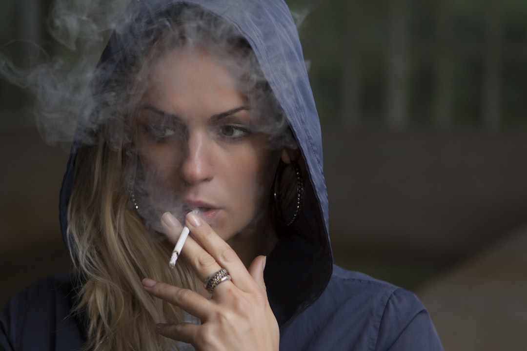 woman wearing hoodie while holding cigarette, Woman in hoodie smoking