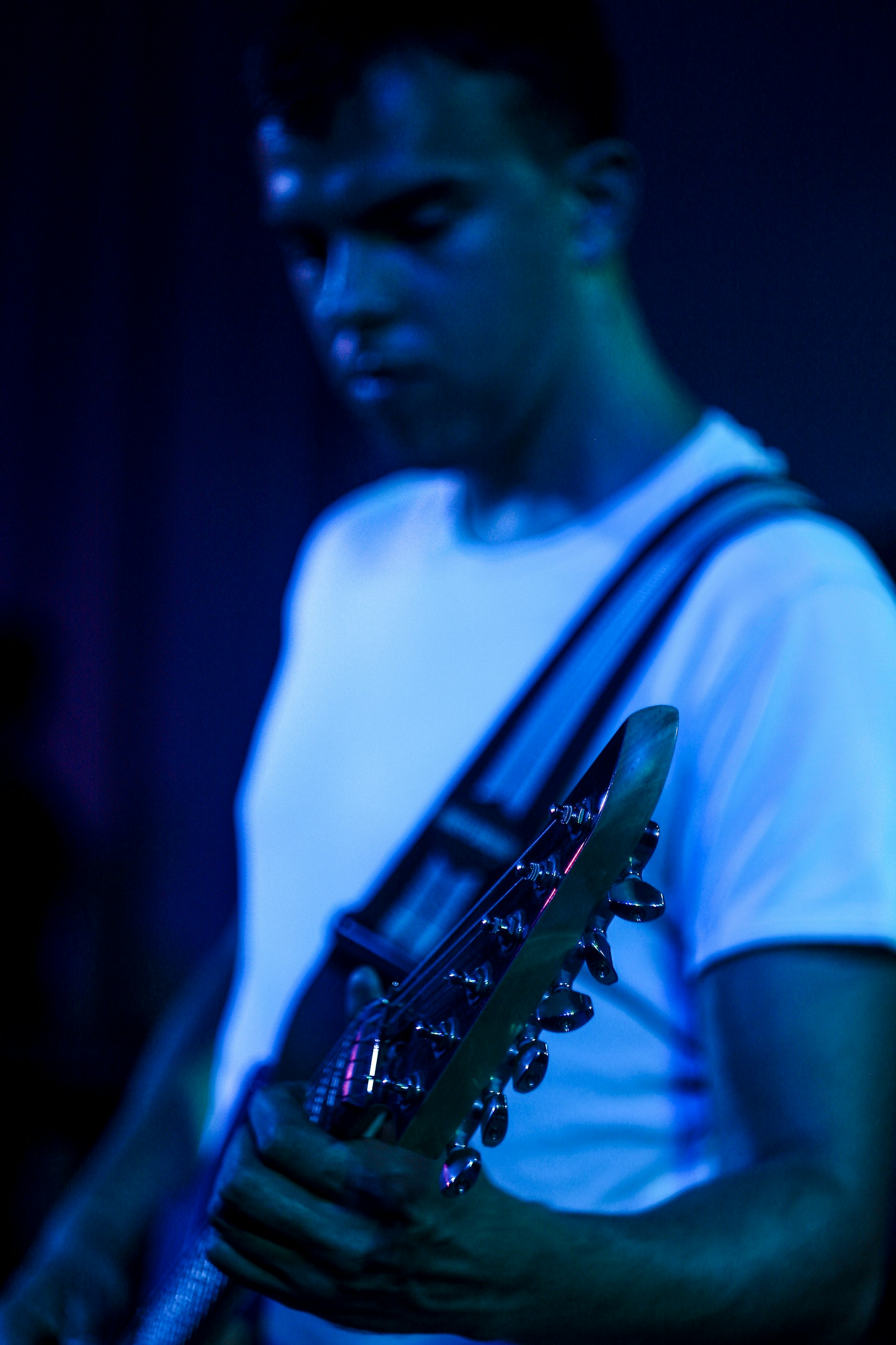 A dynamic shot of a soulful blues guitarist mid-performance, fingers bending strings under moody blue stage lights.