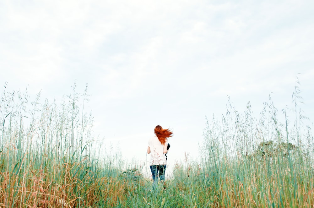 femme debout sur le champ d’herbe verte pendant la journée