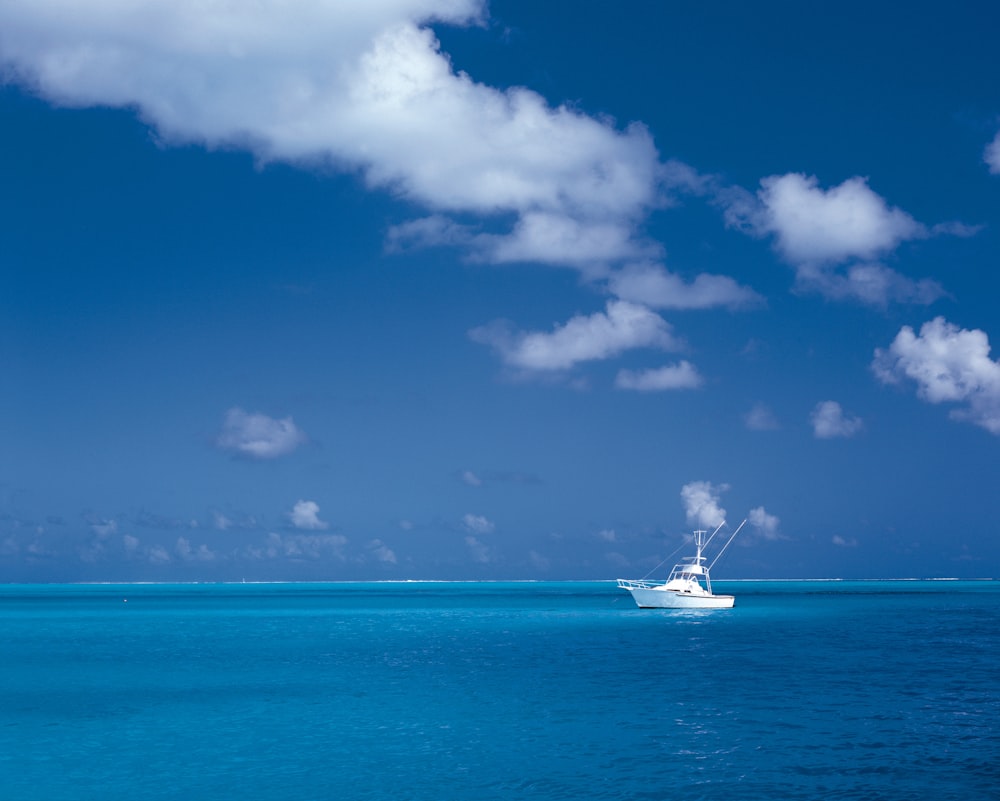 white boat on sea under cloudy sky