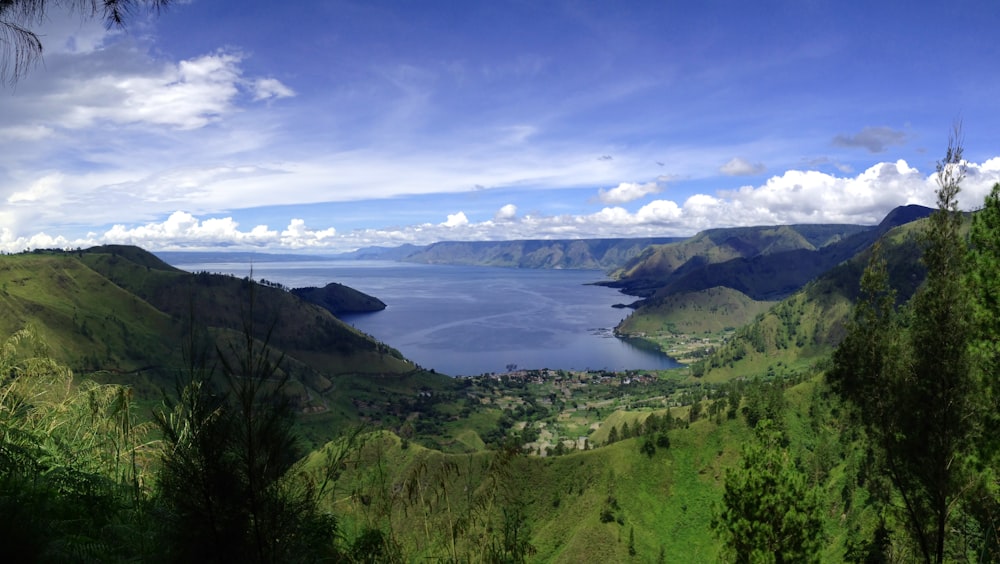 body of water surrounded by green mountains during daytime