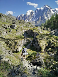 A hiker trekking along a rugged mountain trail with a panoramic view.