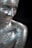 A smiling person is covered in shimmering silver glitter, with some areas reflecting light in blue hues. The focus is on the face and upper body, emphasizing the sparkling texture of the glitter against a dark background.