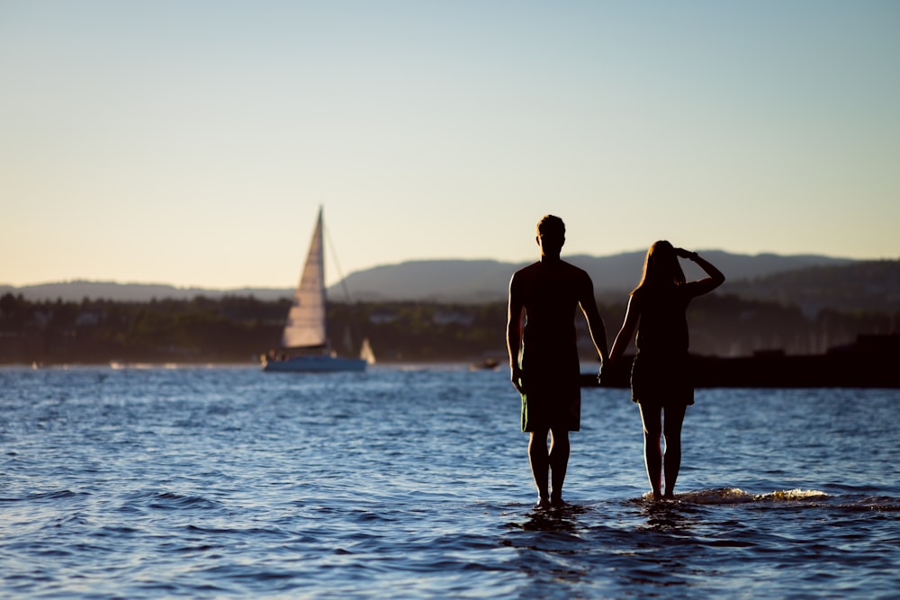 silhouette of man and woman on body of water at daytime