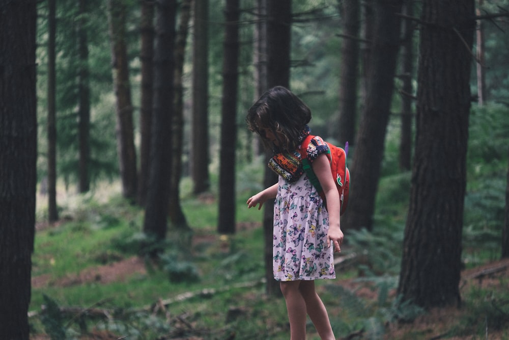 ragazza che cammina nel campo circondato da alberi alti e verdi