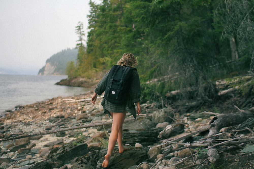 Mujer caminando en la orilla rocosa del mar