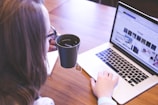 woman holding tea filled mug using MacBook