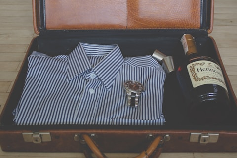 watch, whisky bottle and sport shit in suitcase