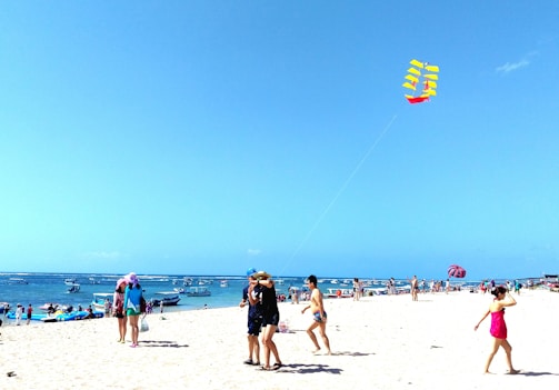 A family enjoying a sunny day at Qingdao’s beach with kite flying.