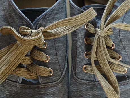 Close-up of colorful shoelaces tangled playfully on a wooden surface.