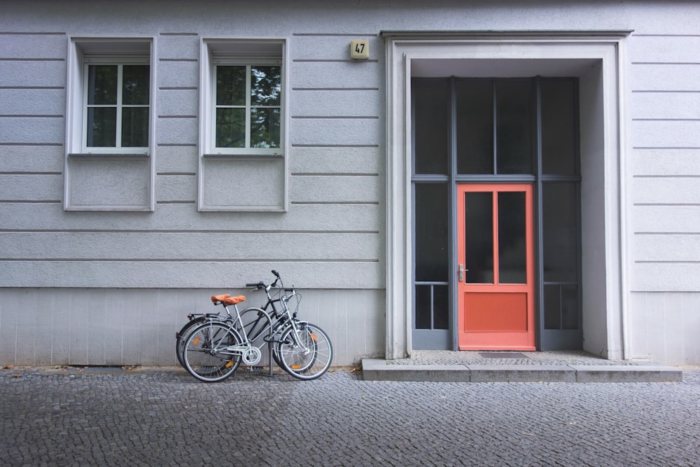 two assorted bicycles near orange door