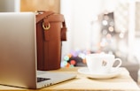 gray laptop beside teacup and bg