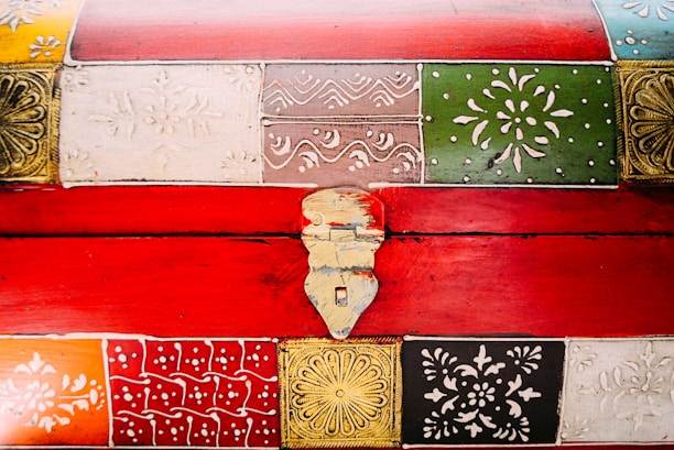 Artisan carefully decorating a wooden chest with colorful, hand-painted designs.
