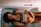 A person is lying in a bathtub filled with water, with slices of oranges placed on their body and around them. The person is wearing a dark sports bra and appears relaxed with eyes closed. The setting is minimalistic with white tiles surrounding the tub.