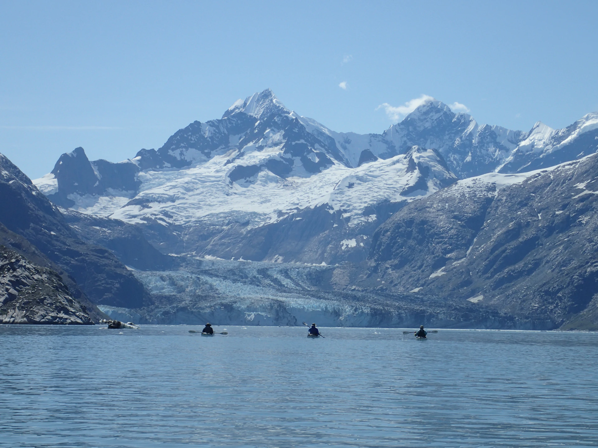 A panoramic shot of a kayak gliding through crystal-clear waters surrounded by towering glaciers in Patagonia, capturing raw nature and adventure.