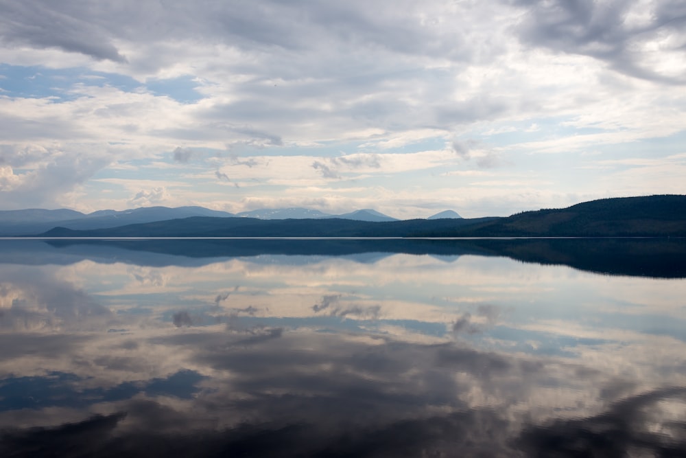 calm body of water near mountain