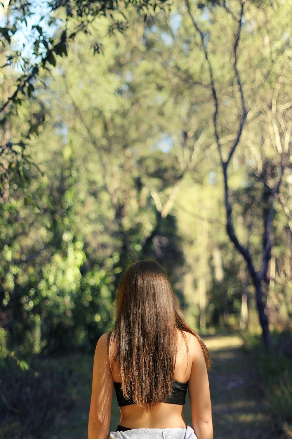 Frau trägt schwarzen Sport-BH mit Blick auf den Wald