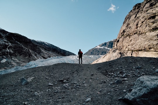 person standing on hill during daytime in Nigardsbreen Norway